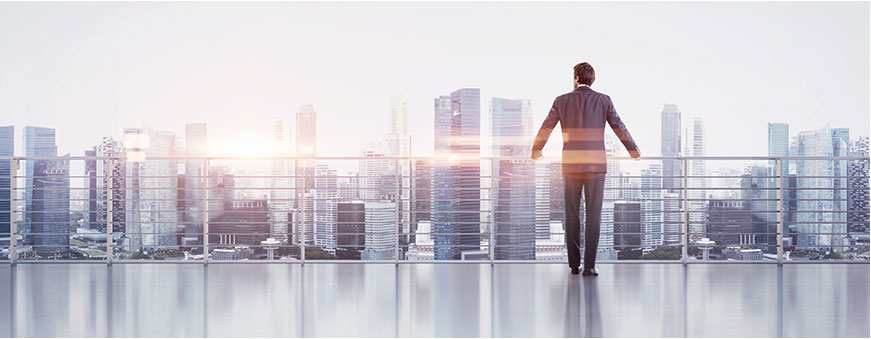 A man standing on the balcony of his apartment looking at the city.